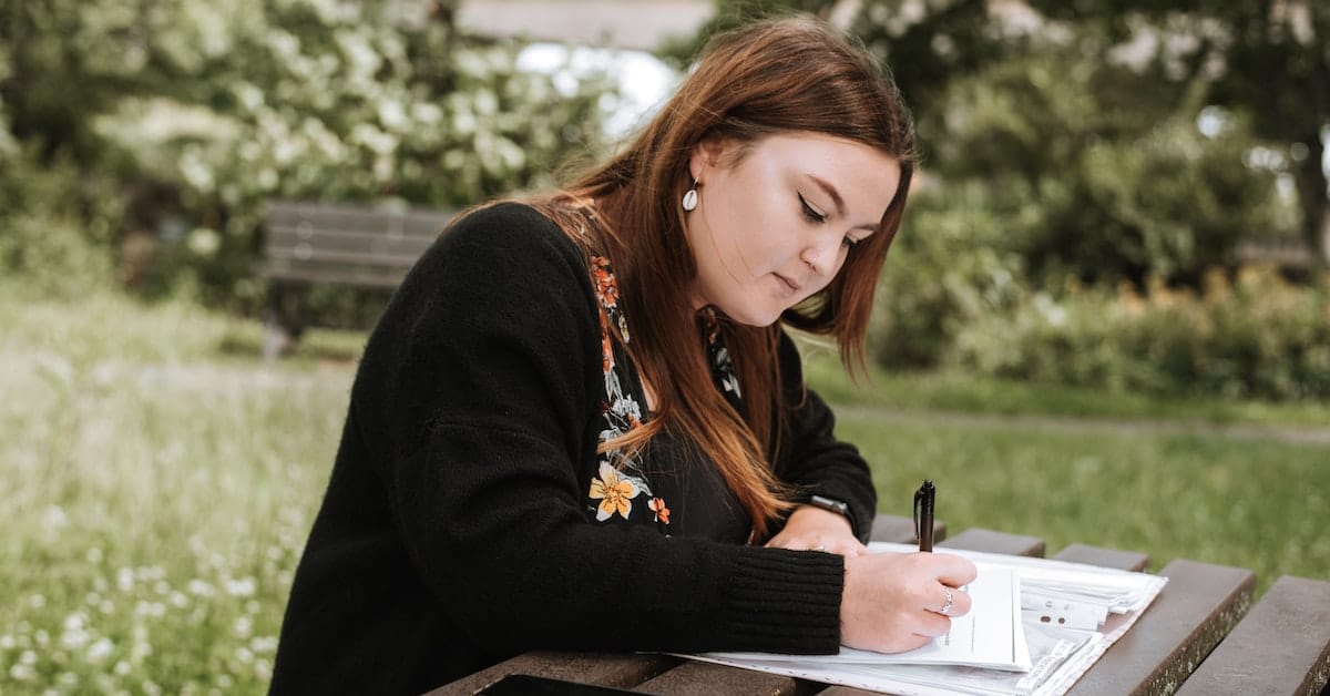 woman sitting outside writing an outline for a blog post