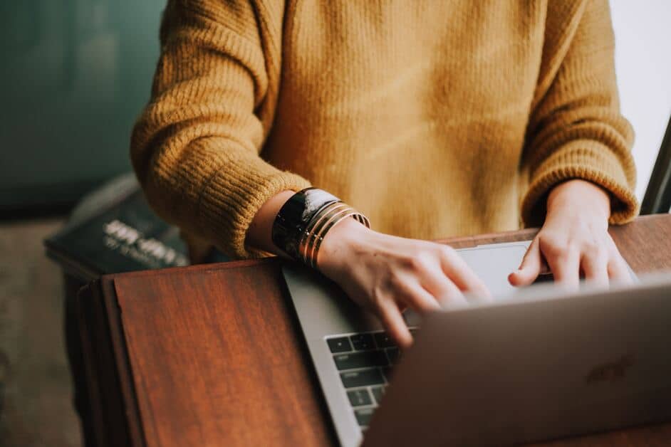 getting writing jobs that pay as a beginner woman on laptop at desk in yellow sweater