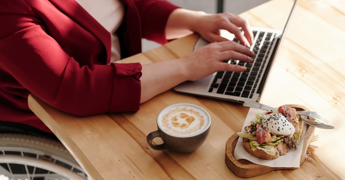 woman working as a freelance writer on laptop with coffee and breakfast