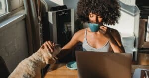 woman drinking coffee and petting dog working in high paying freelance writer niche