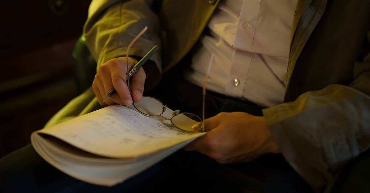 man with glasses using writer's notebook