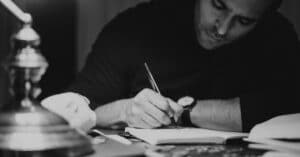 black and white photo of man using writer's notebook
