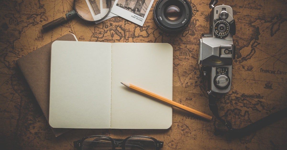 writer's notebook with pencil camera magnifying glass and other objects