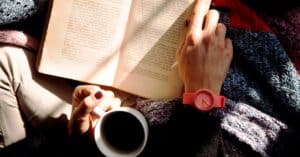 person reading wearing watch drinking coffee
